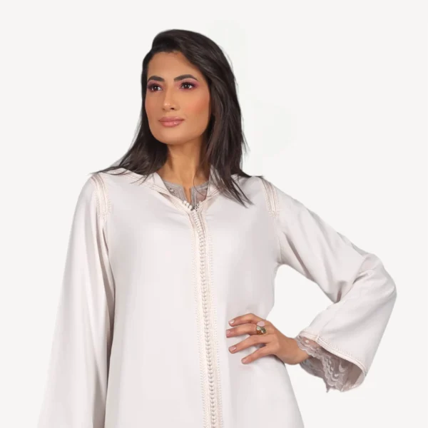 Djellaba Hanaa Mautassin blanche, confectionnée en crêpe fluide avec dentelle délicate et zwak maalem, idéale pour les mariages et occasions prestigieuses.