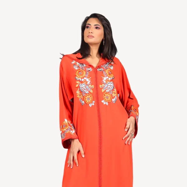 Djellaba Jawaher Mautassin en crêpe orange vibrant, ornée de broderies délicates, une pièce artisanale idéale pour les occasions spéciales.