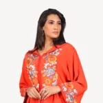 Djellaba Jawaher Mautassin en crêpe orange vibrant, ornée de broderies délicates, une pièce artisanale idéale pour les occasions spéciales.